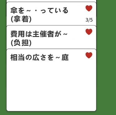 3张同类词卡牌。文字分别是「傘を~・っている(拿着)」「費用は主催者が~(負担)」「相当の広さを~庭」。